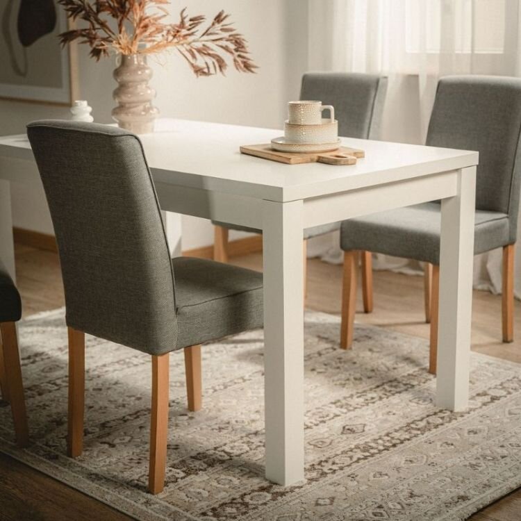 Světlý obývací pokoj se stolem a židlemi pro celou rodinu. 