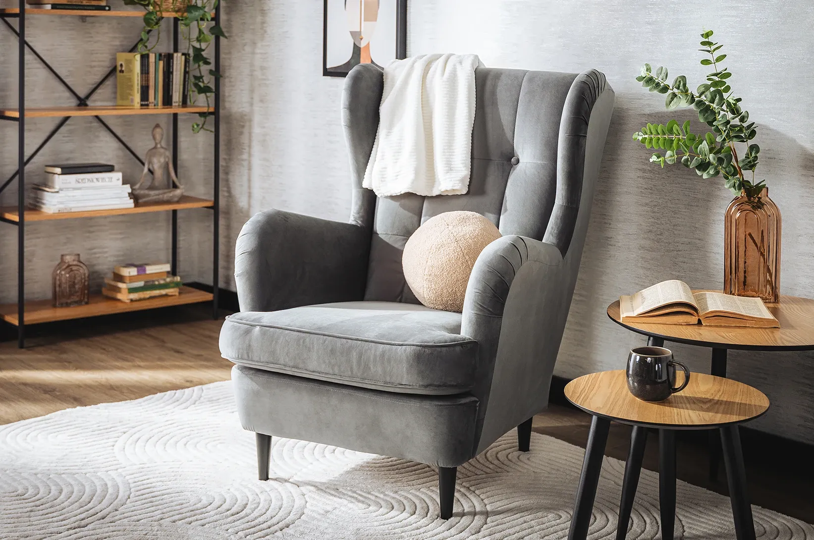 Šedé křeslo s dekou a polštáři. 