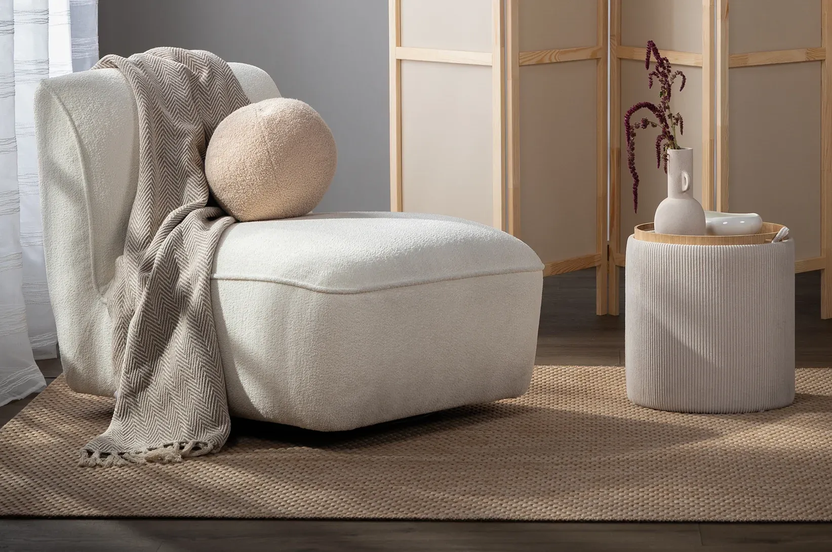 Bílý křeslo s kulatým polštářem. 