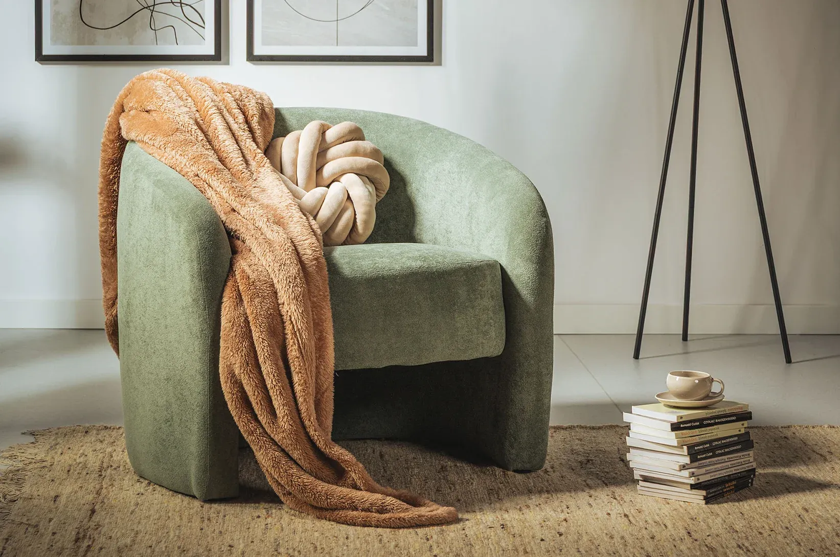 Zelené křeslo s polštářem a dekou.