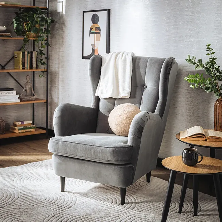 Šedé křeslo s dekou a polštáři. 