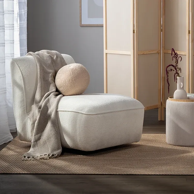 Bílý křeslo s kulatým polštářem. 