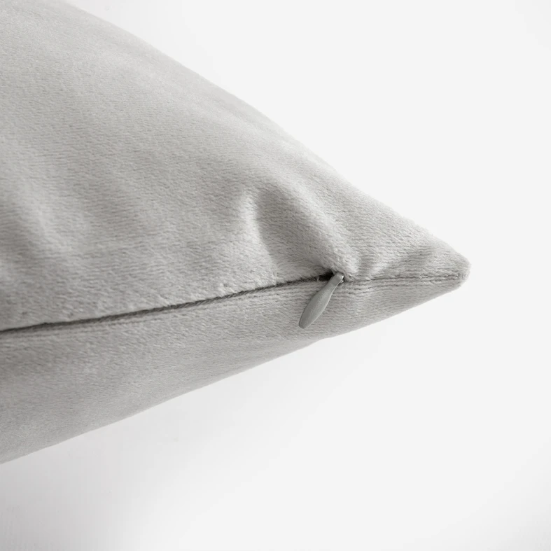 Zbliżenie na róg jasnoszarej poszewki, widoczne staranne wykończenie i uchwyt zamka w kolorze poszewki. 