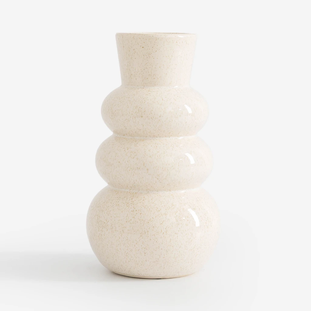 Ceramiczny wazon w kolorze kremowym. Obłości przypominają sylwetkę bałwanka. Nakrapiany drobnymi jasnobrązowymi piegami.