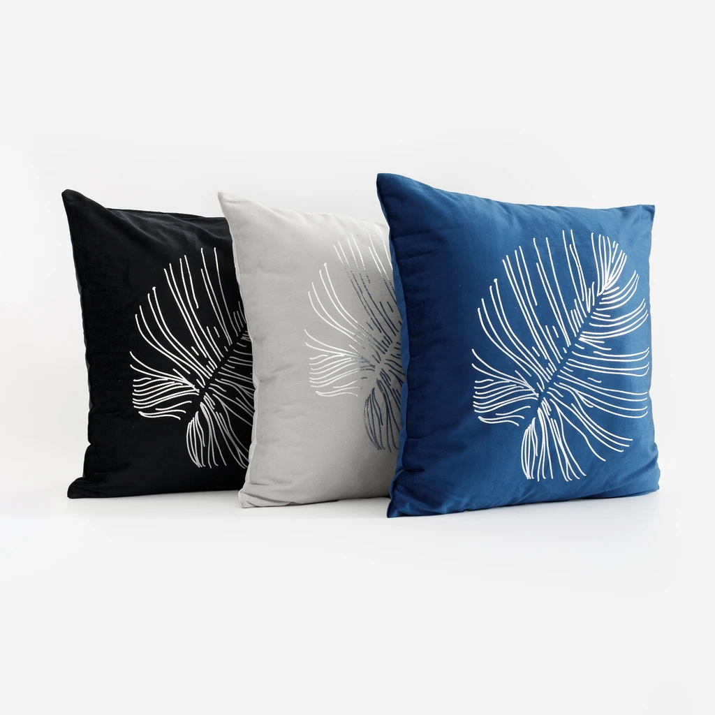 Trzy poszewki dekoracyjne z kolekcji Saona pionowo, jedna za drugą, czarna, jasnoszara i ciemnoniebieska. 