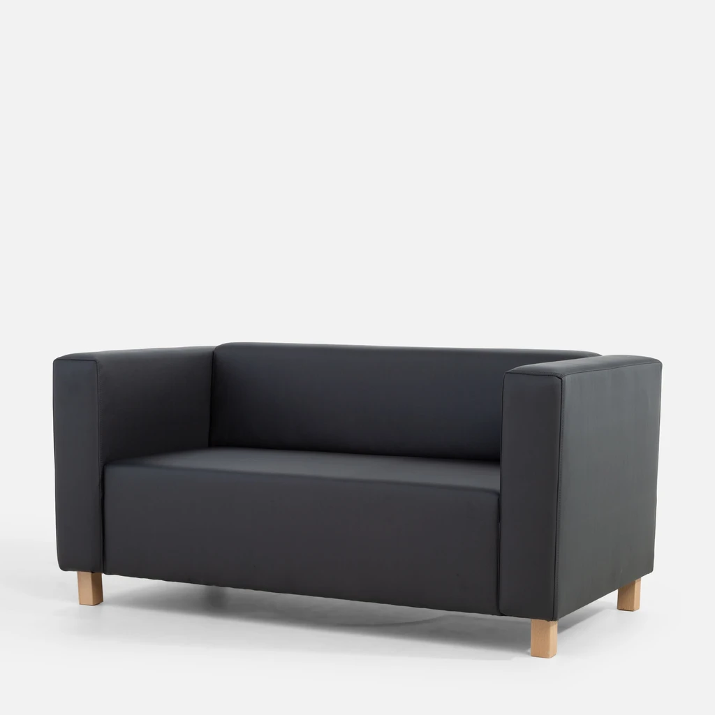 Grafitowa, bryłowata sofa widziana z ukosa.