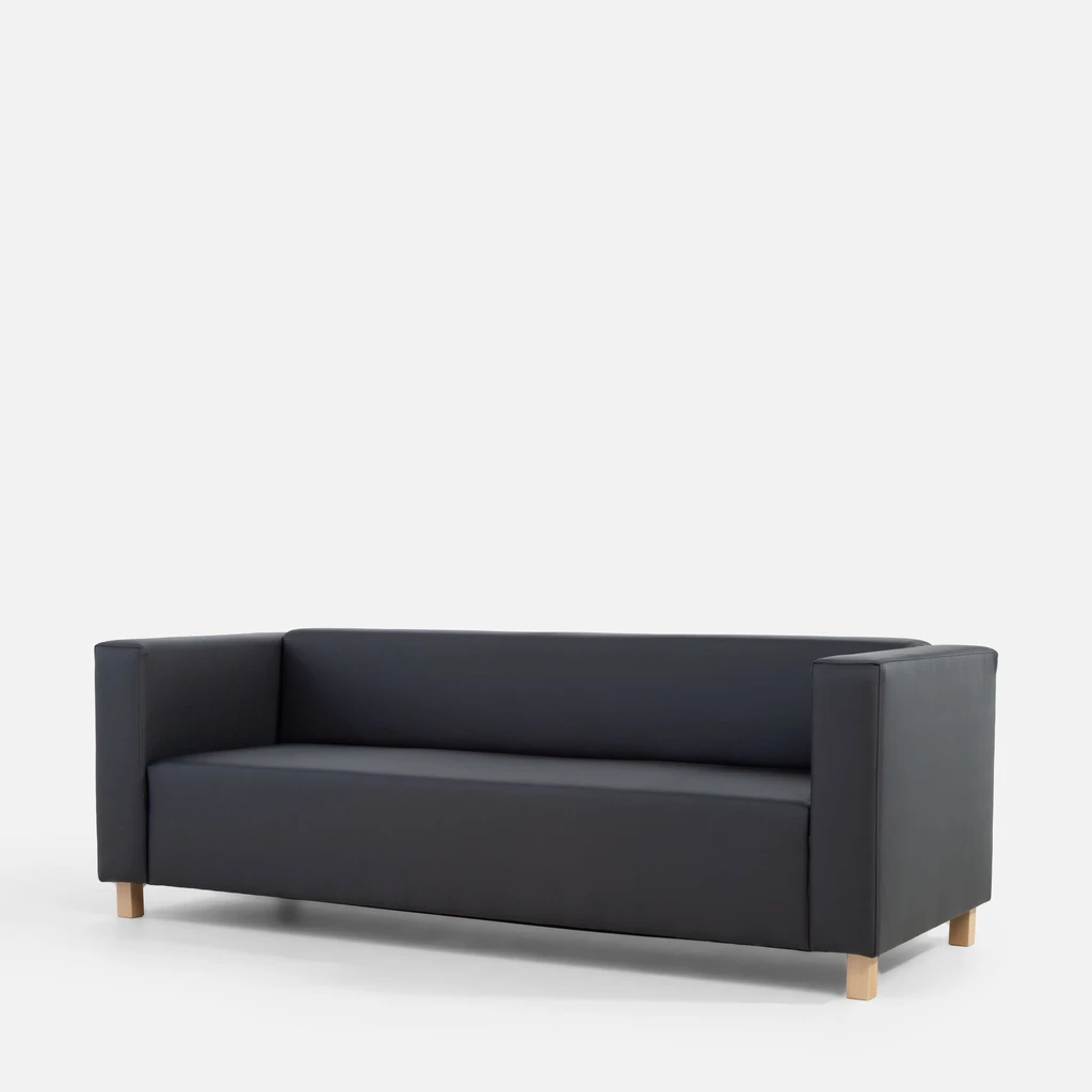 Grafitowa, bryłowata sofa widziana z ukosa.