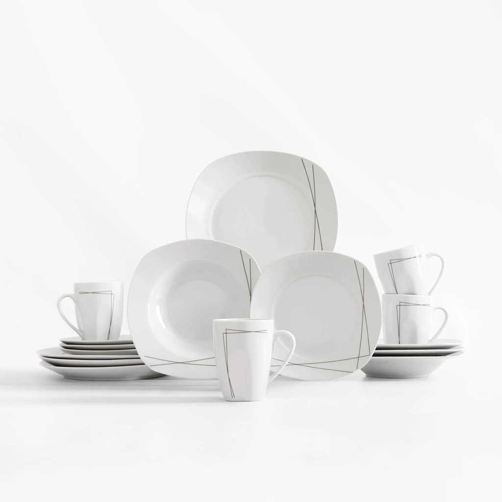 Zestaw obiadowy z delikatnym geometrycznym wzorem kreślonym cienką, ciemnoszarą linią na białej porcelanie. Widoczne talerze obiadowe, głębokie i deserowe oraz kubki.