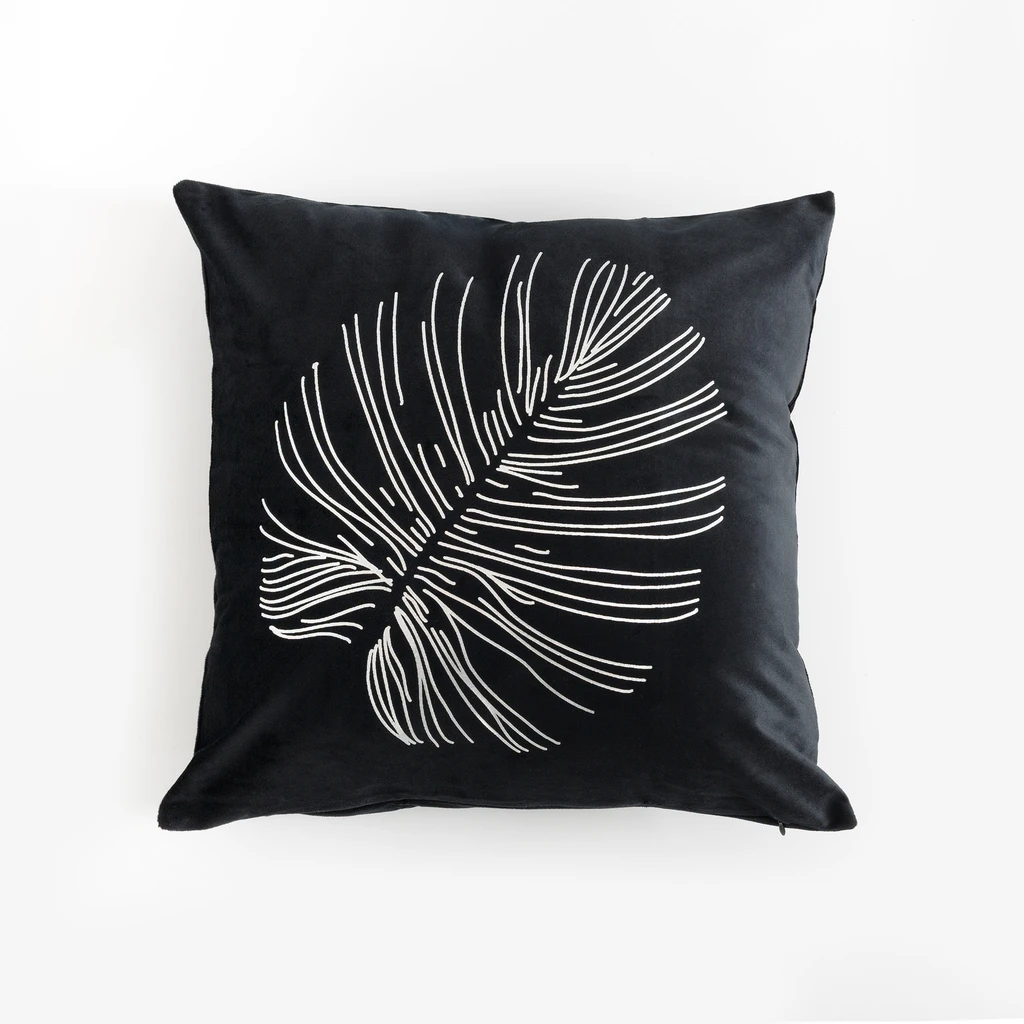 Czarna, kwadratowa poszewka dekoracyjna z poliestru przypominającego welur, ze srebrnym nadrukiem liścia monstery. 