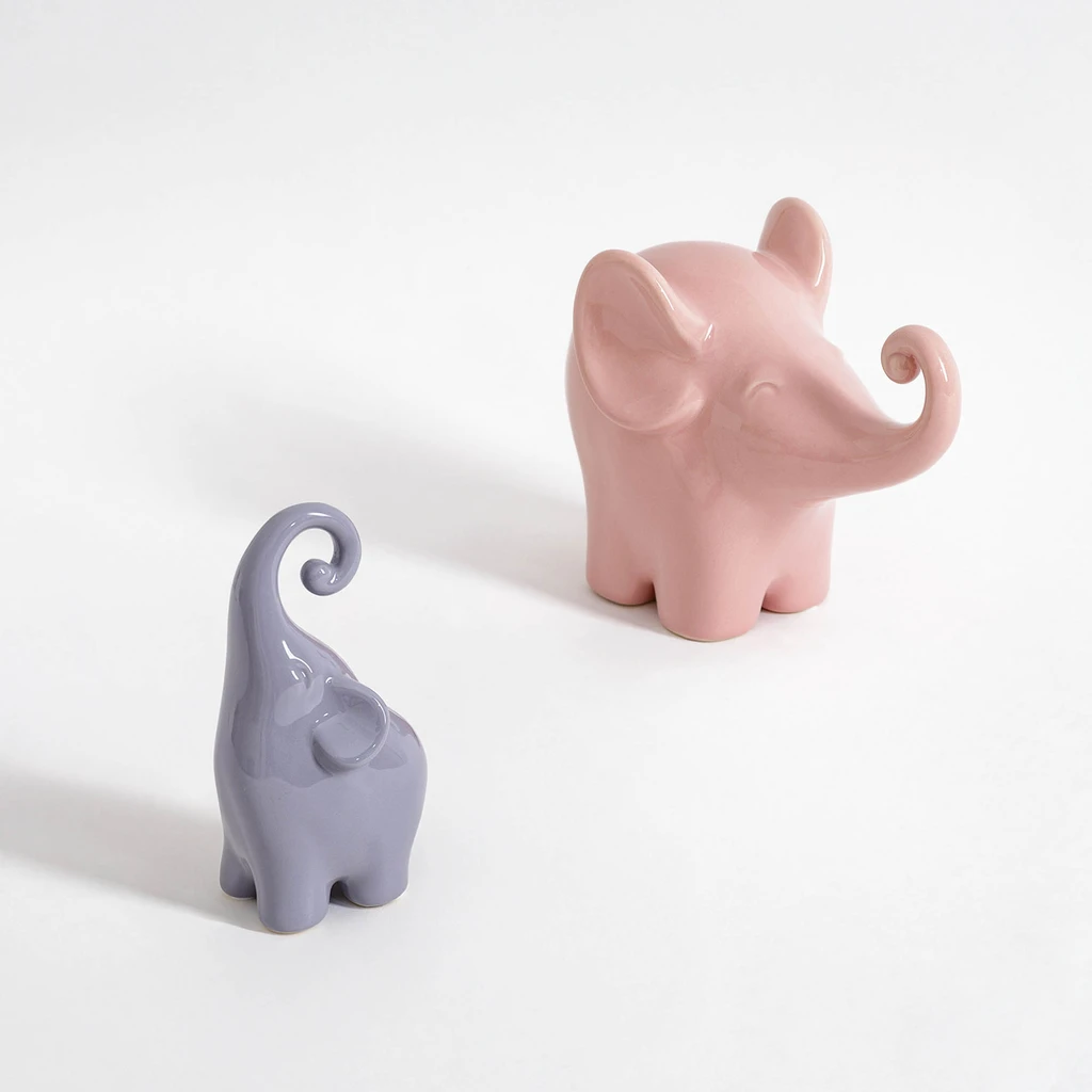 Różowy słonik z radośnie uniesioną trąbą.