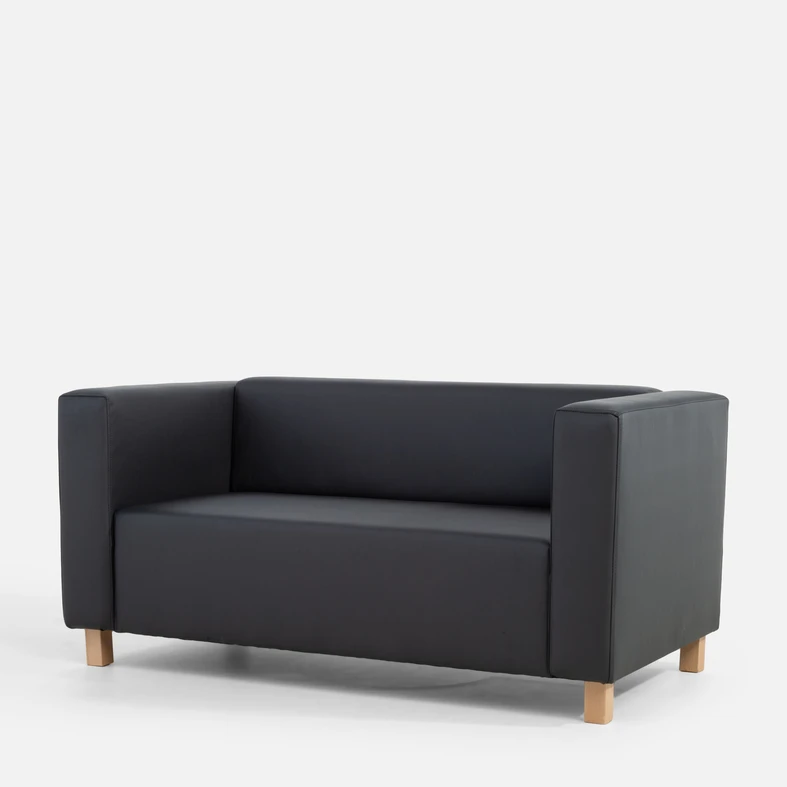 Grafitowa, bryłowata sofa widziana z ukosa.