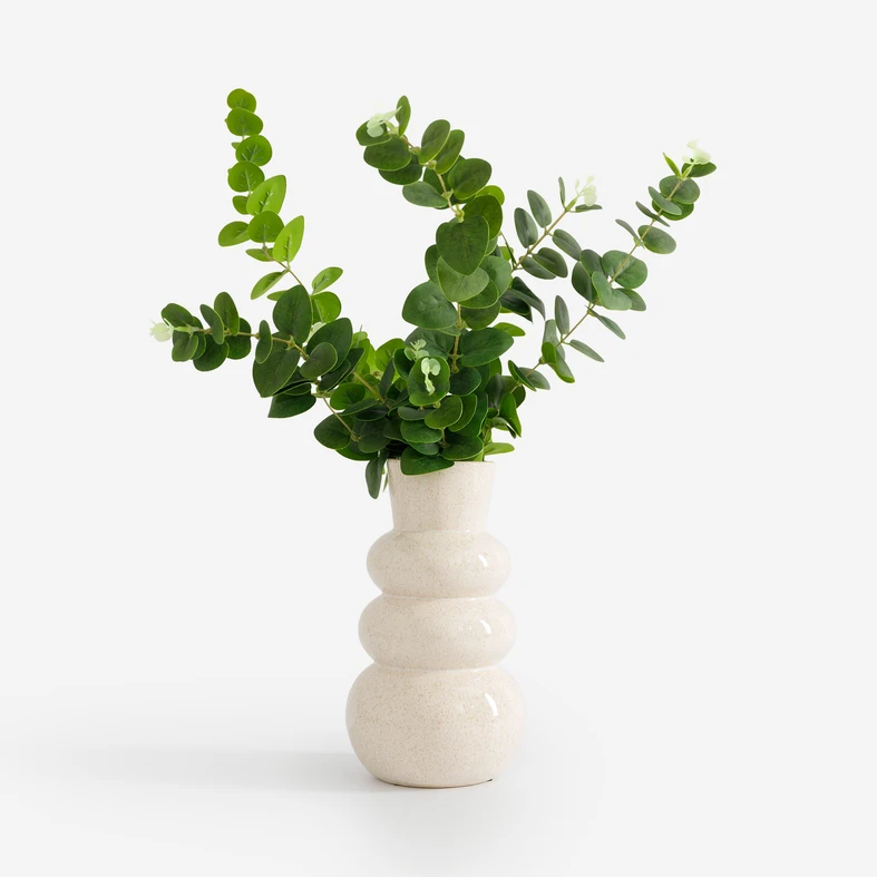Gałązki eukaliptusa w kremowym wazonie ceramicznym. 