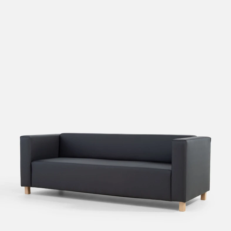 Grafitowa, bryłowata sofa widziana z ukosa.