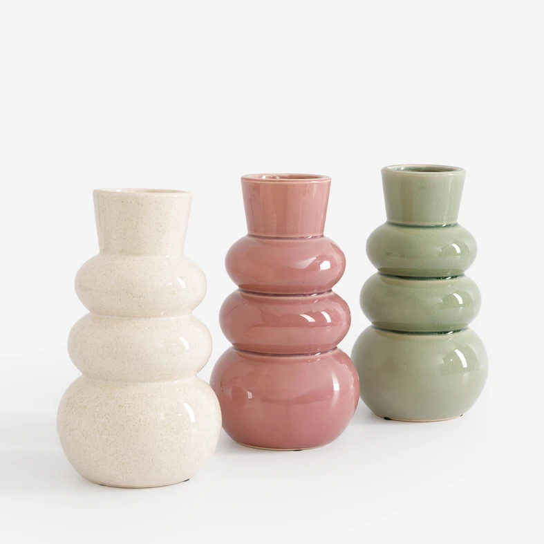 Trzy gładkie, ceramiczne wazony swoim kształtem przypominające sylwetkę bałwanka. Od lewej kremowy, zgaszony róż i jasnozielony, każdy z połyskiem. 