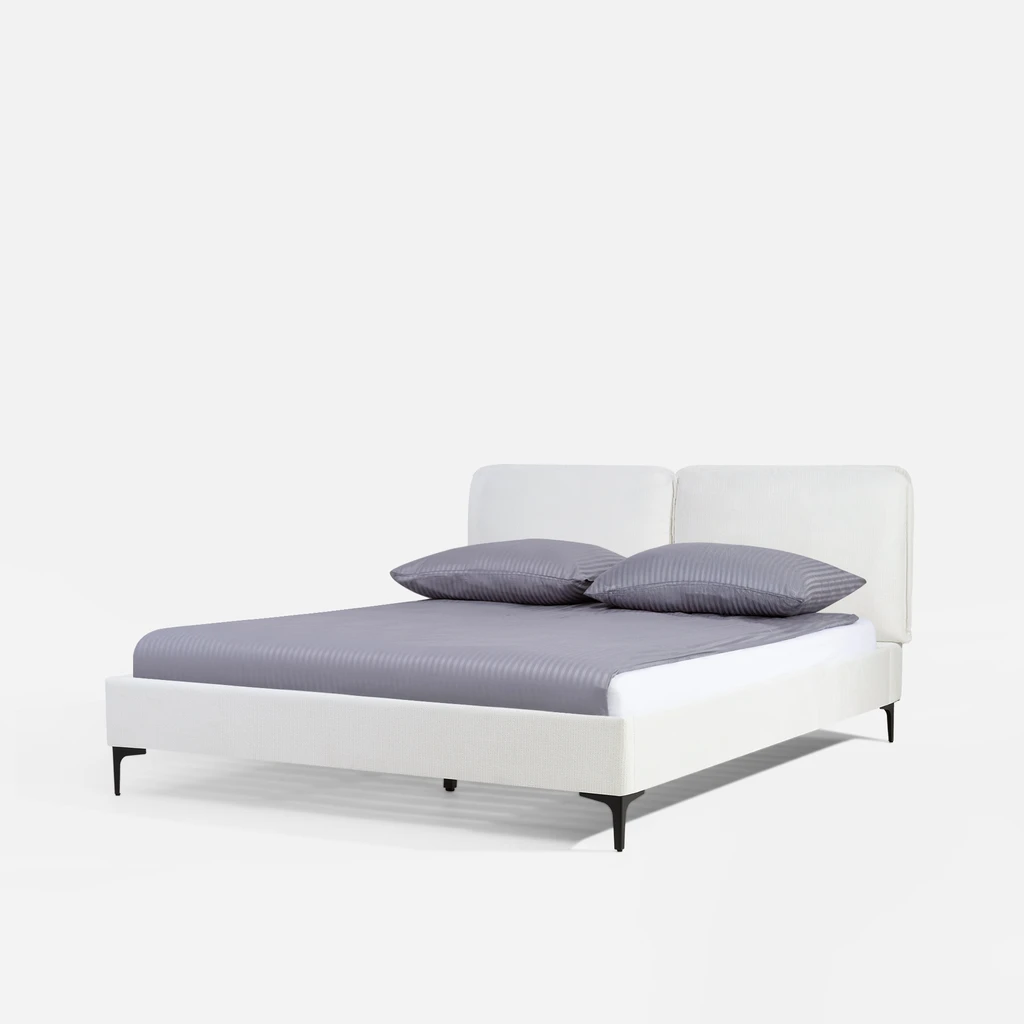 Widok na łóżko od strony szczytu dolnego, z ukosa. Na łóżku materac i srebrzystoszara pościel.