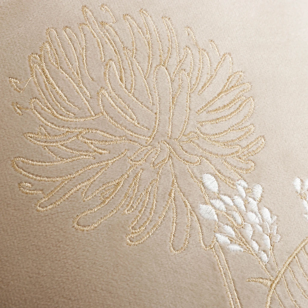 Zbliżenie na wyszywany wzór, widoczna beżowa i biała nić. 