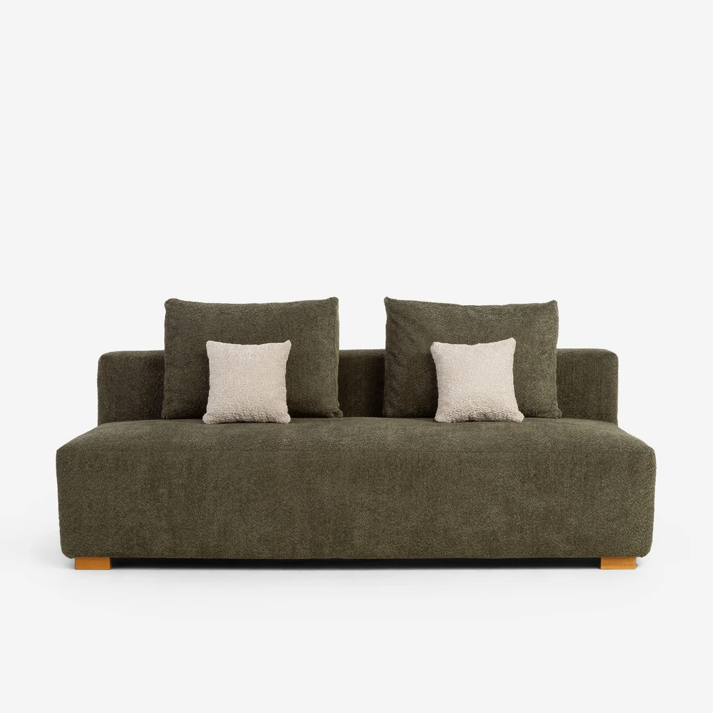 Zielona sofa z poduszkami oparciowymi w tej samej tkaninie i dwoma małymi beżowymi