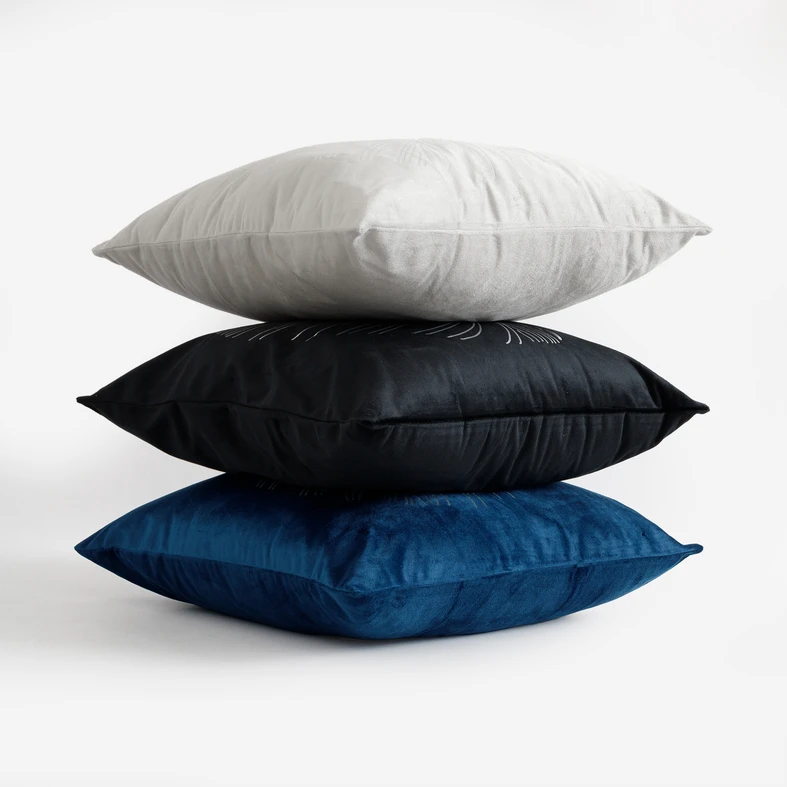 Trzy poduszki z kolekcji Saona ułożone jedna na drugiej. 