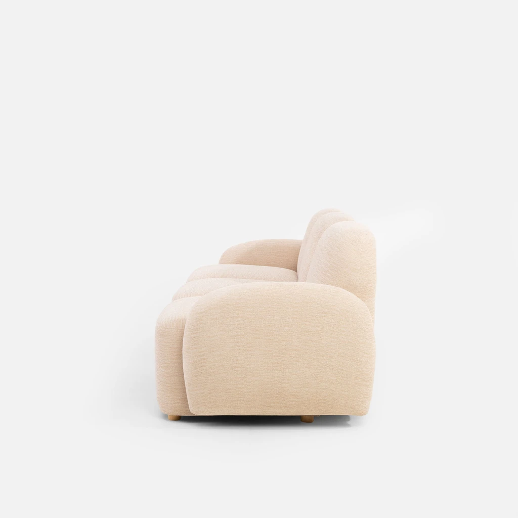 Bok beżowej sofy z widocznym zaokrąglonym podłokietnikiem