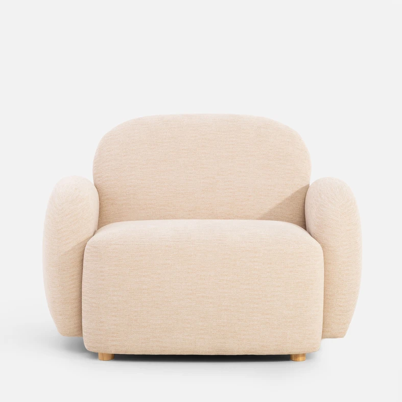Beżowy fotel o obłych kształtach, z niskimi nóżkami z jasnego drewna - widok od przodu
