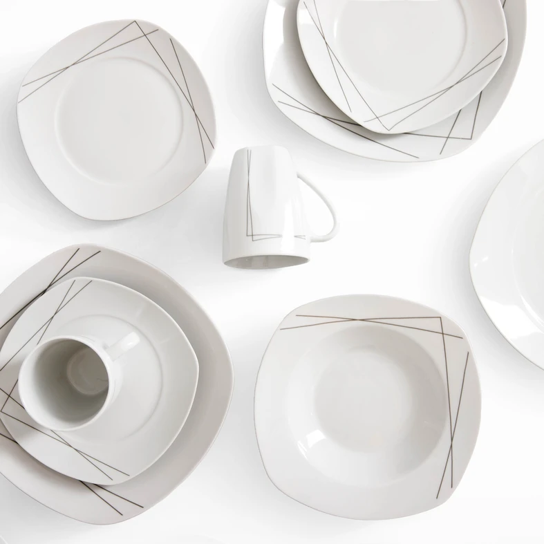 Rzut z góry, zestaw obiadowy z delikatnym geometrycznym wzorem kreślonym cienką, ciemnoszarą linią na białej porcelanie. Naczynia mają lekko kwadratowy kształt.