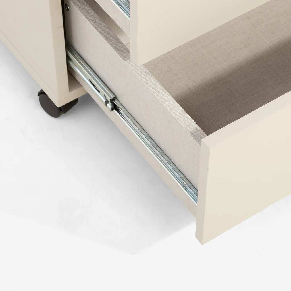 Szafka z dwiema szufladami sprawdzi się zarówno przy łóżku, jak i w biurze. Ciepły odcień uchwytów subtelnie ożywia wnętrze, a kółka ułatwiają przemieszczanie.