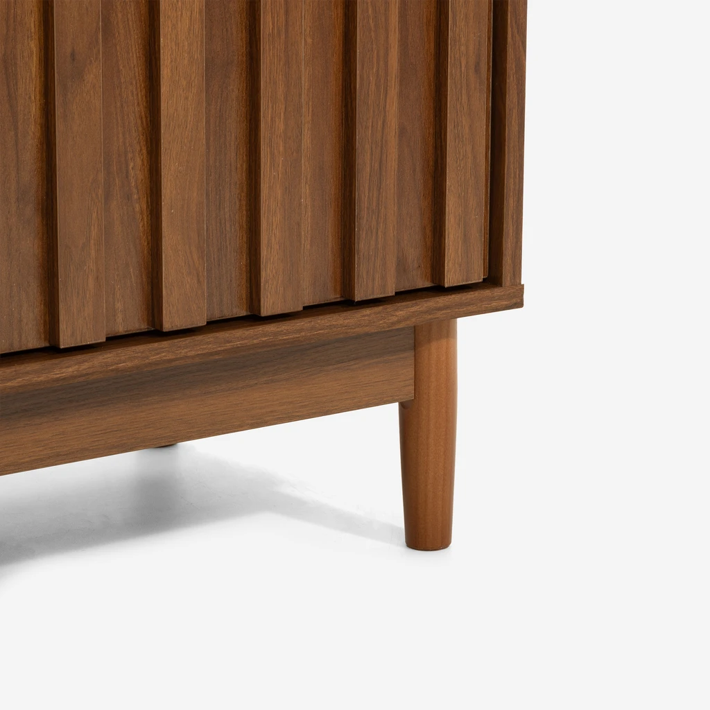 Detal, dolna część mebla z widocznymi drewnianymi nóżkami i ryflowaniem na froncie