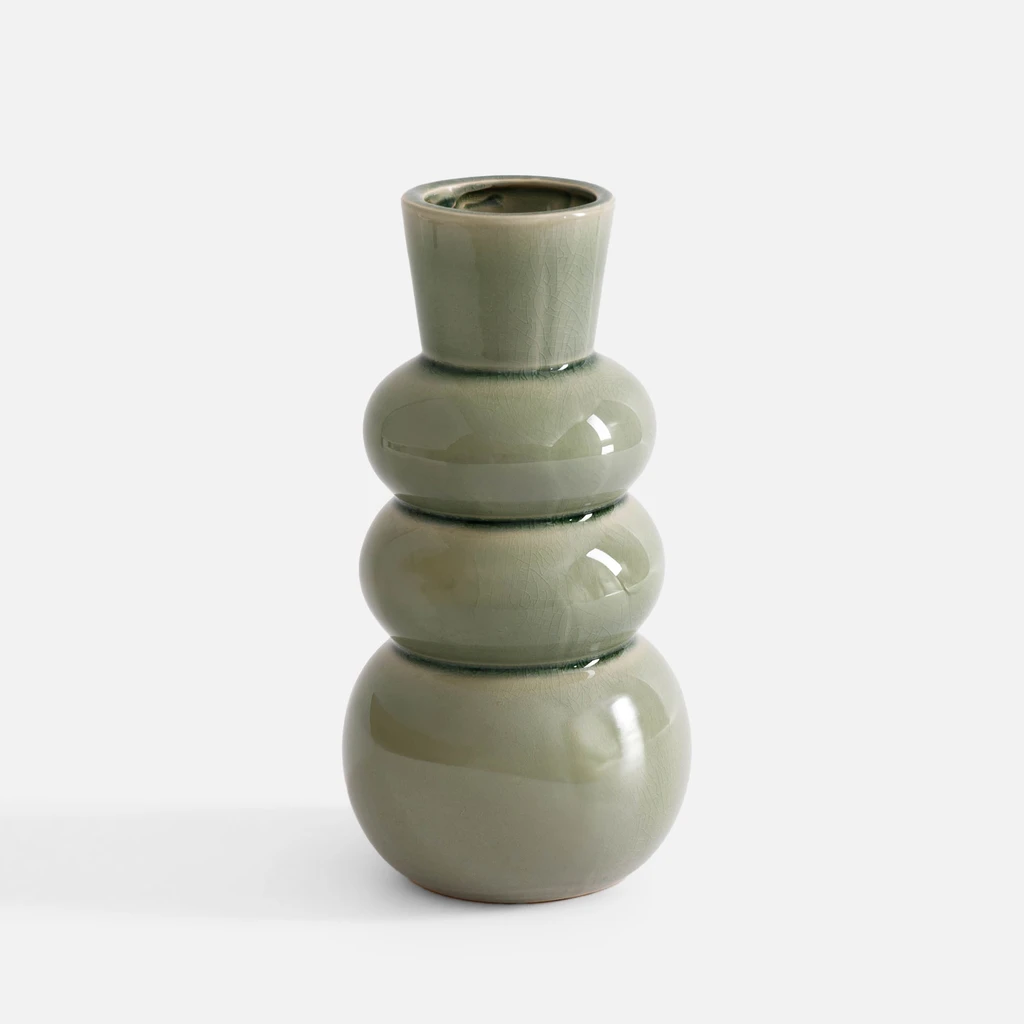 Ceramiczny, jasnozielony wazon z połyskiem, o bąbelkowym kształcie, przypominający nieco bałwanka. Widok od frontu. 