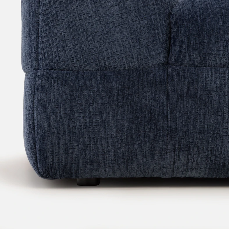 Detal, zbliżenie na dół sofy z widocznymi niskimi, czarnymi nóżkami