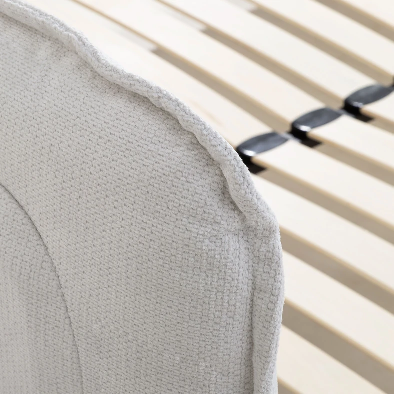 Zbliżenie na staranne wykończenie wysokiego zagłówka obitego białą tkaniną.