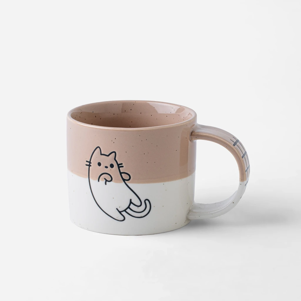 Porcelanowy kubek, w połowie brudny róż, w połowie biel. Na ściance kontur kotka. Kubek ma szerokie ucho. 