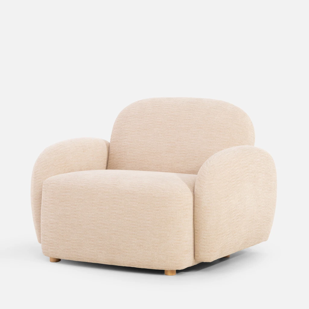 Beżowy fotel o obłych kształtach, z niskimi nóżkami z jasnego drewna