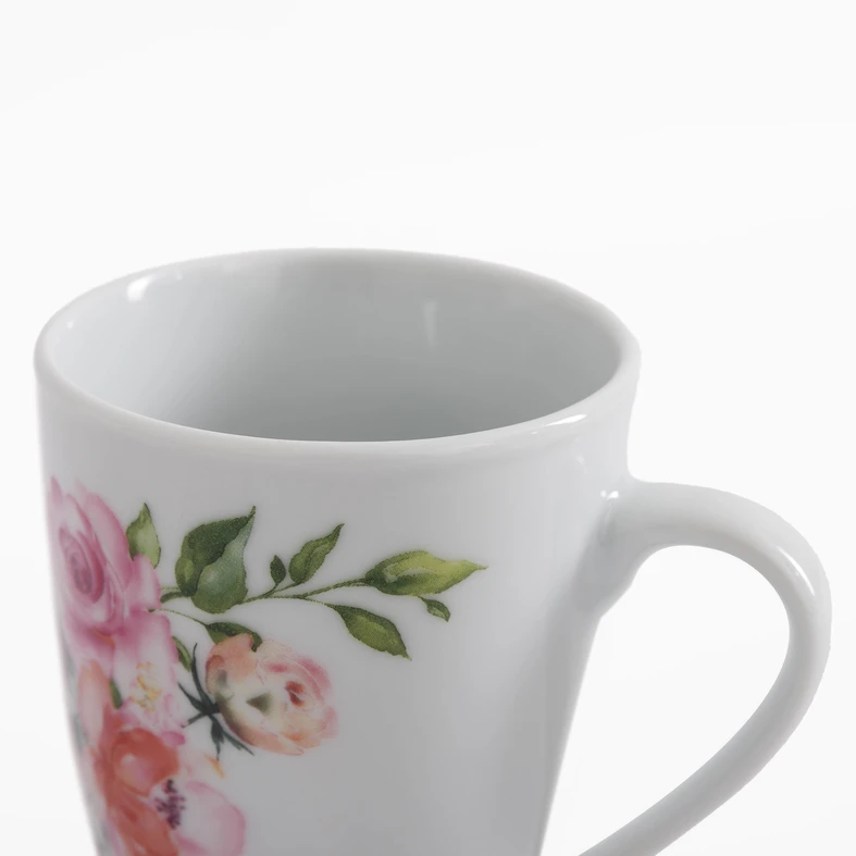 Detal kubka, kwiatowy wzór na białej porcelanie. Różowo-koralowe róże i zielone listki.