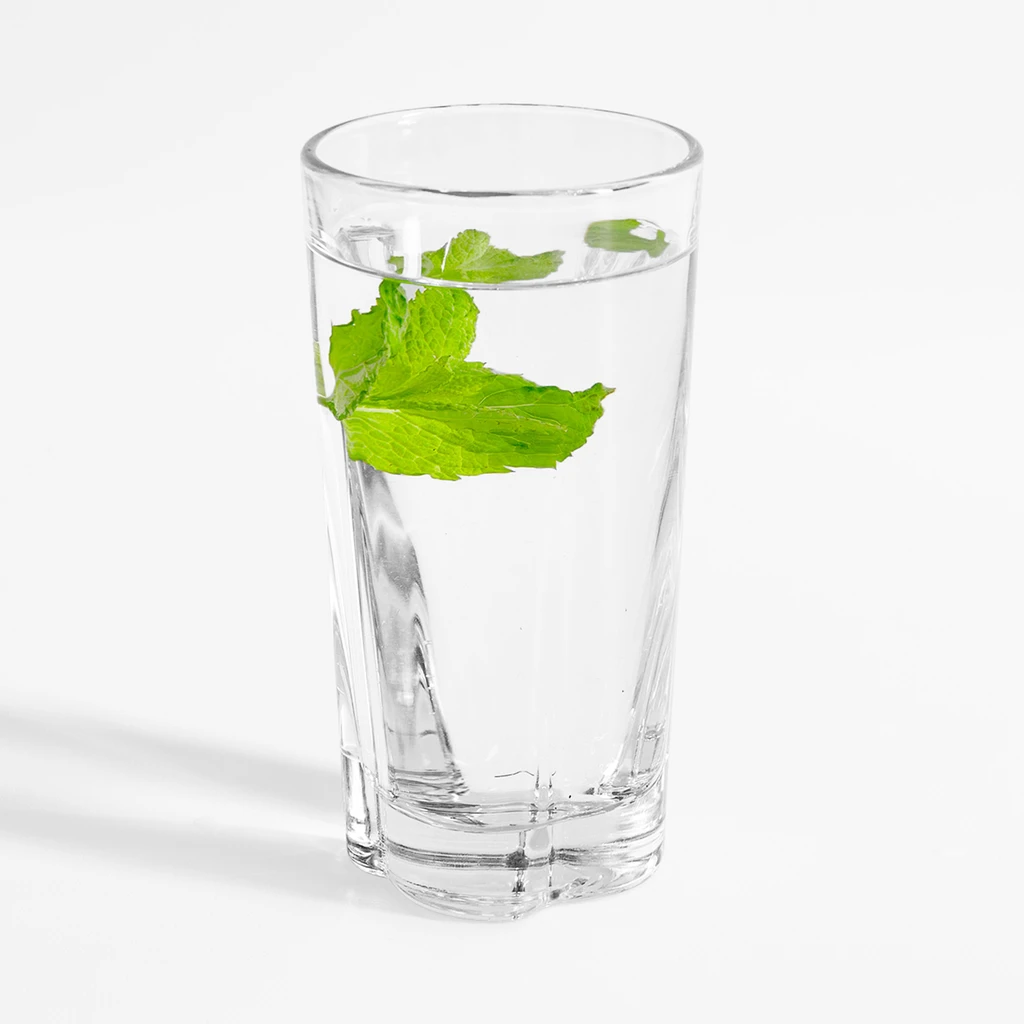 Zdjęcie użytkowe, wysoka szklanka long drink, w wodzie zanurzone listki mięty.